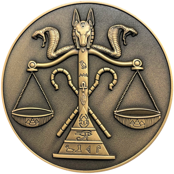 Gold metal coin showing jackal head and cobras on top of scale with Egyptian symbols