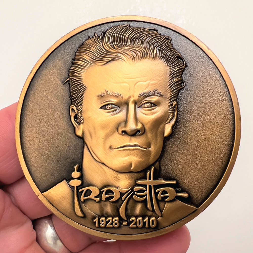 Copper metal coin in hand showing Frazetta portrait, name, and years 1928-2010