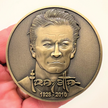 Gold metal coin in hand showing Frank Frazetta portrait, his name, and year 1928-2010