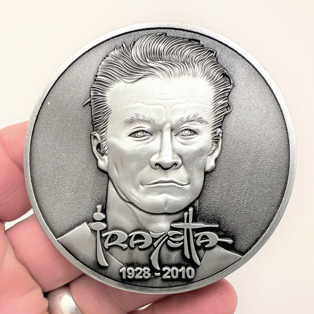 Silver metal coin showing Frazetta portrait with name and years 1928-2010