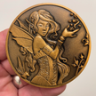 Copper metal coin in hand showing Fairy with frog