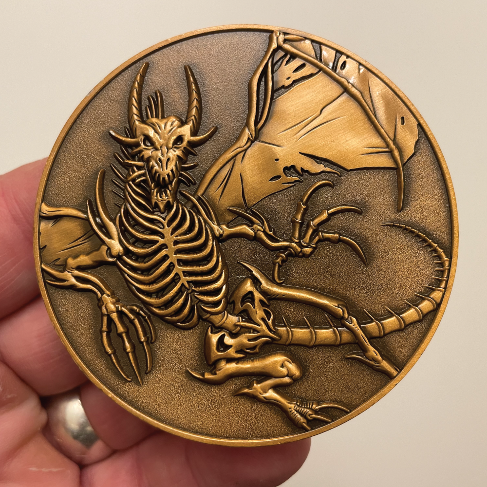 Copper metal coin in hand showing skeleton dragon