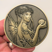 Gold metal coin in hand showing fairy with ball in fairy hand