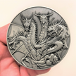 Silver metal coin in hand showing Five Headed Dragon