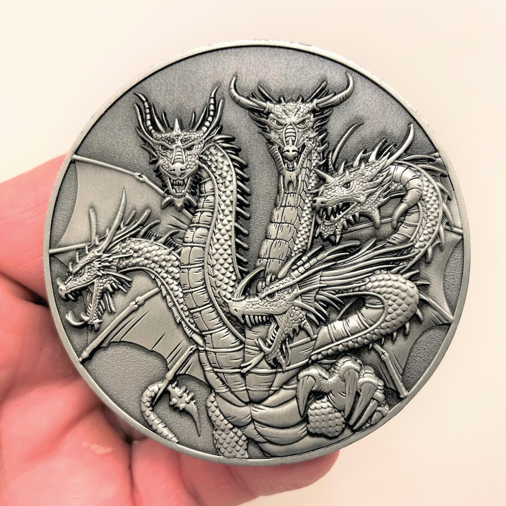 Silver metal coin in hand showing Five Headed Dragon