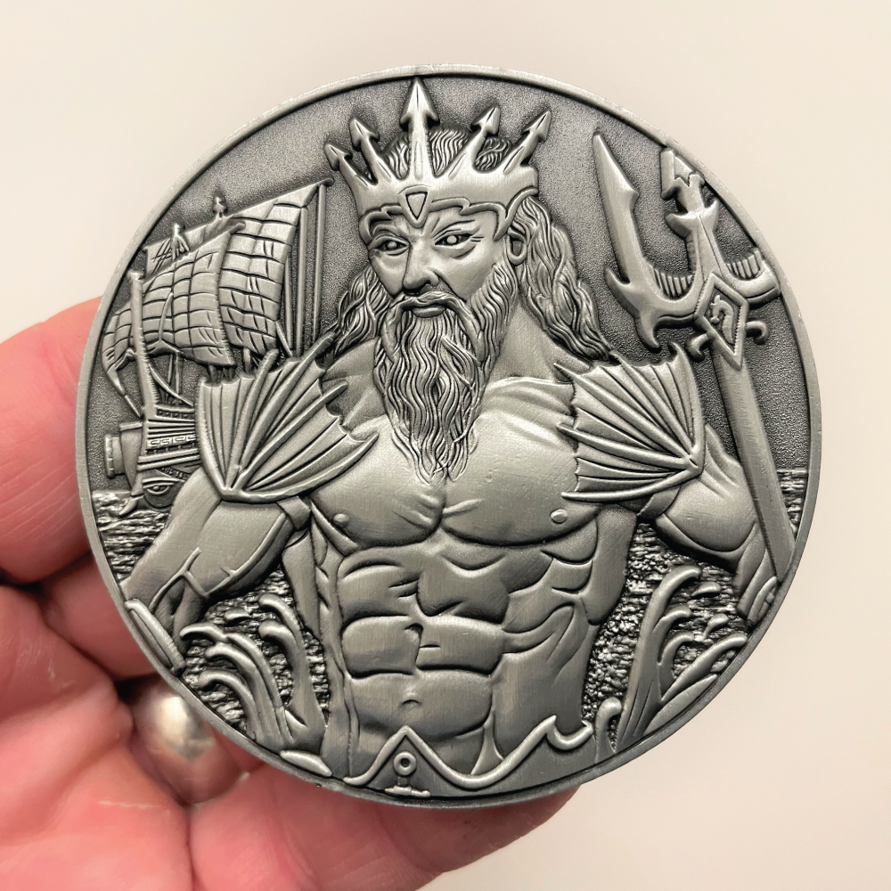 Silver metal coin in hand showing Poseidon