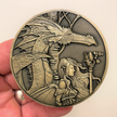 Gold metal coin in hand showing fairy and dragon next to her